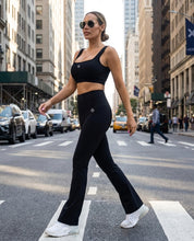 Woman in black athletic wear crossing a city street.